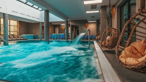 Basen termalny z kaskadą wodną i wiszącymi fotelami – Termy Gorce