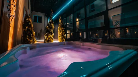Zewnętrzne jacuzzi nocą z fioletowym podświetleniem – Termy Gorce
