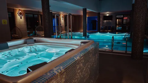 Jacuzzi wewnętrzne z mozaikową okładziną przy nocnym oświetleniu – Termy Gorce